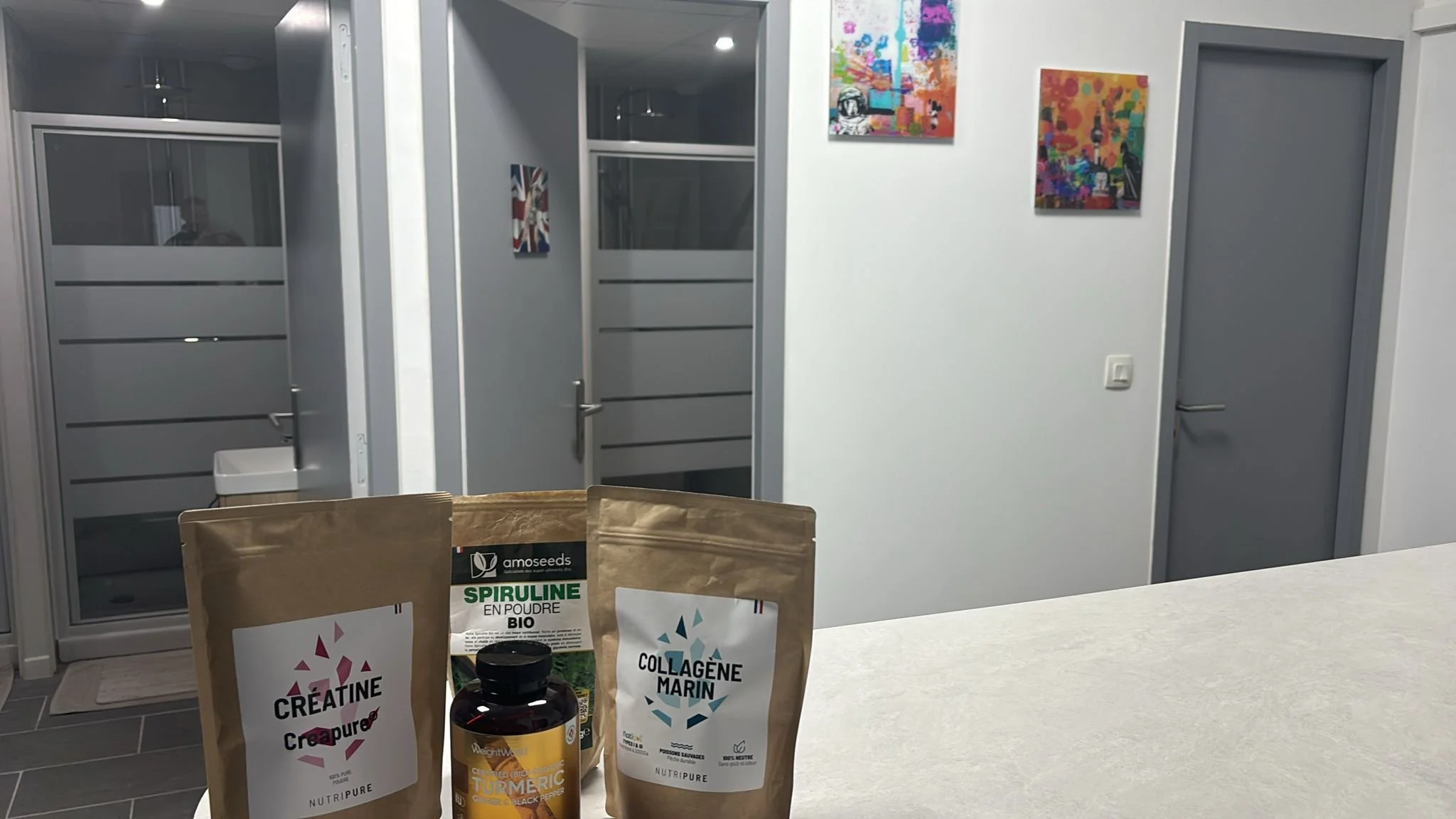 Suppléments en poudre pour la santé, incluant créatine, spiruline, collagène marin et un comprimé de curcuma, sur une table.