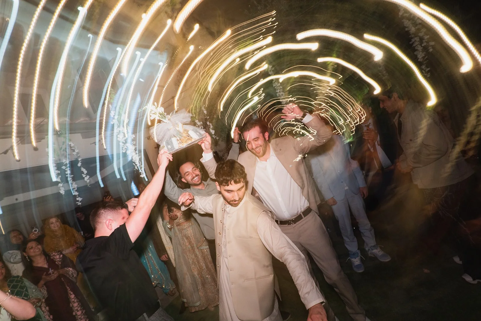 People dancing and celebrating at a party with colorful lights and energetic atmosphere.