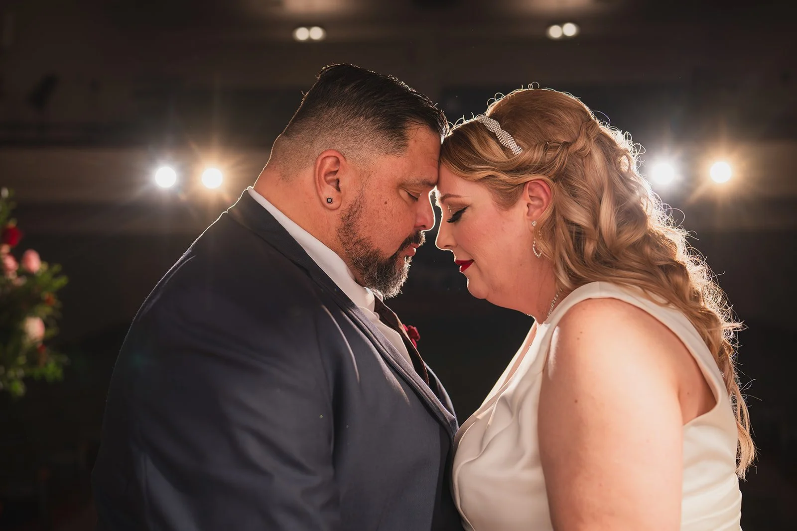 A couple dressed in wedding attire with their foreheads touching during their wedding ceremony.