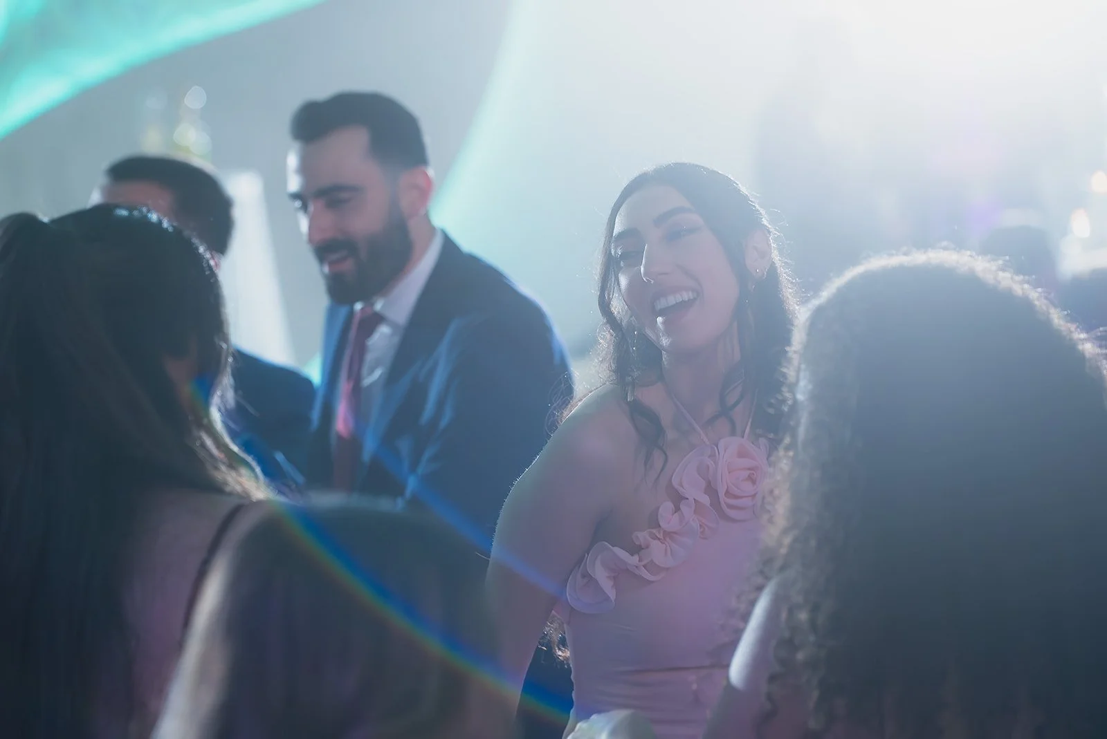 People dancing and socializing at a party with bright lights and a festive atmosphere.