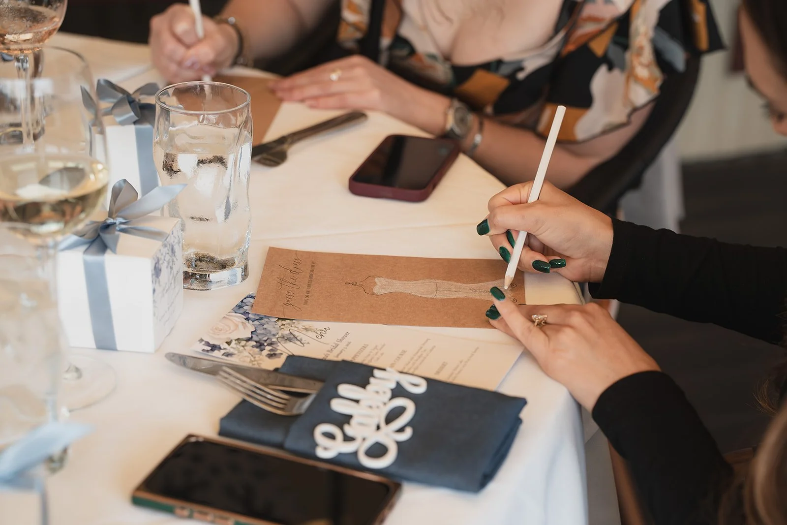 Person signing a wedding invitation at a table set for a celebration.