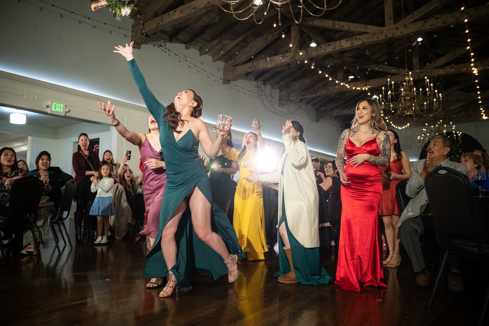Celebration scene at a wedding reception with women dancing and guests watching, lively atmosphere with smiles.