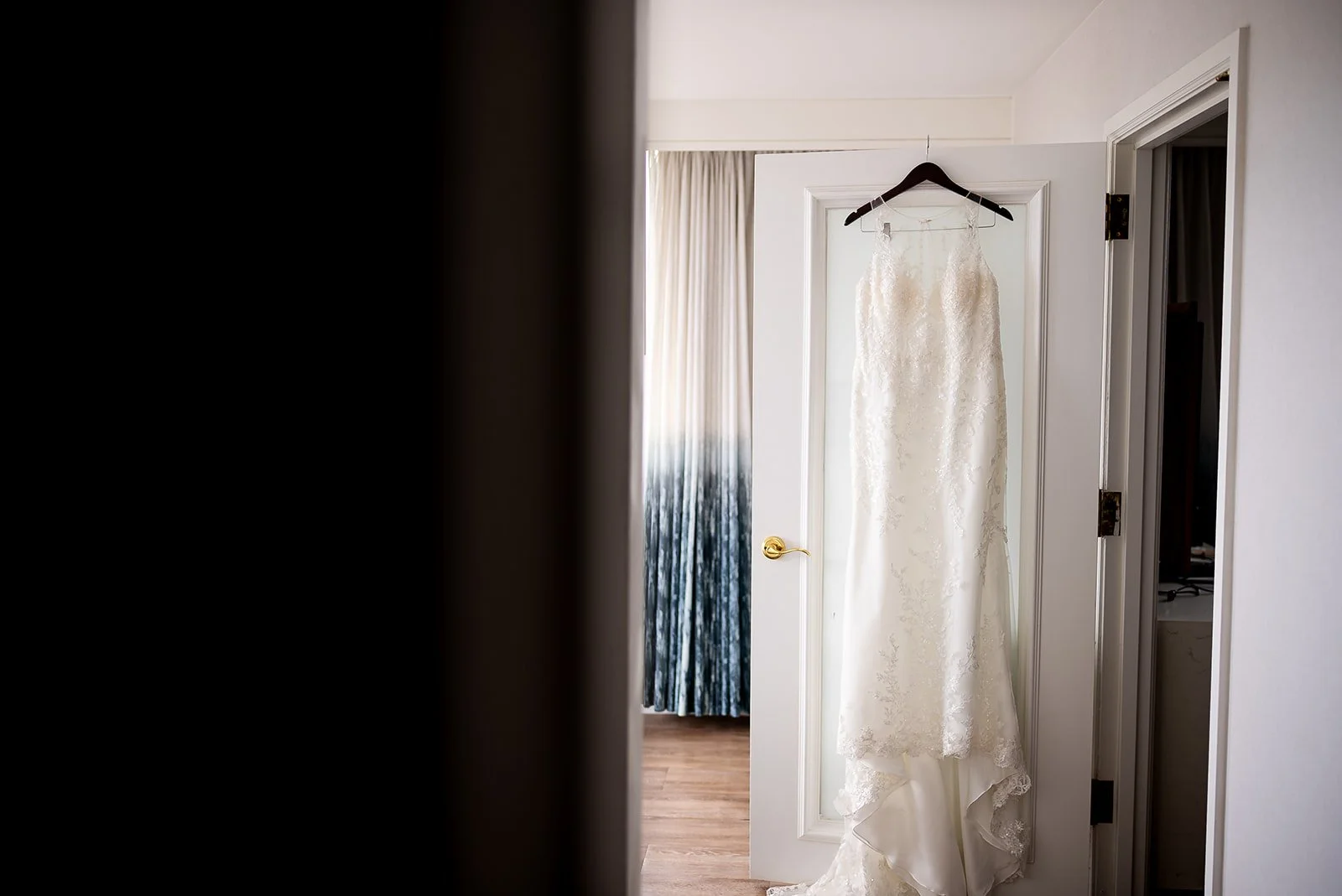 A wedding dress hanging on a door in a room.