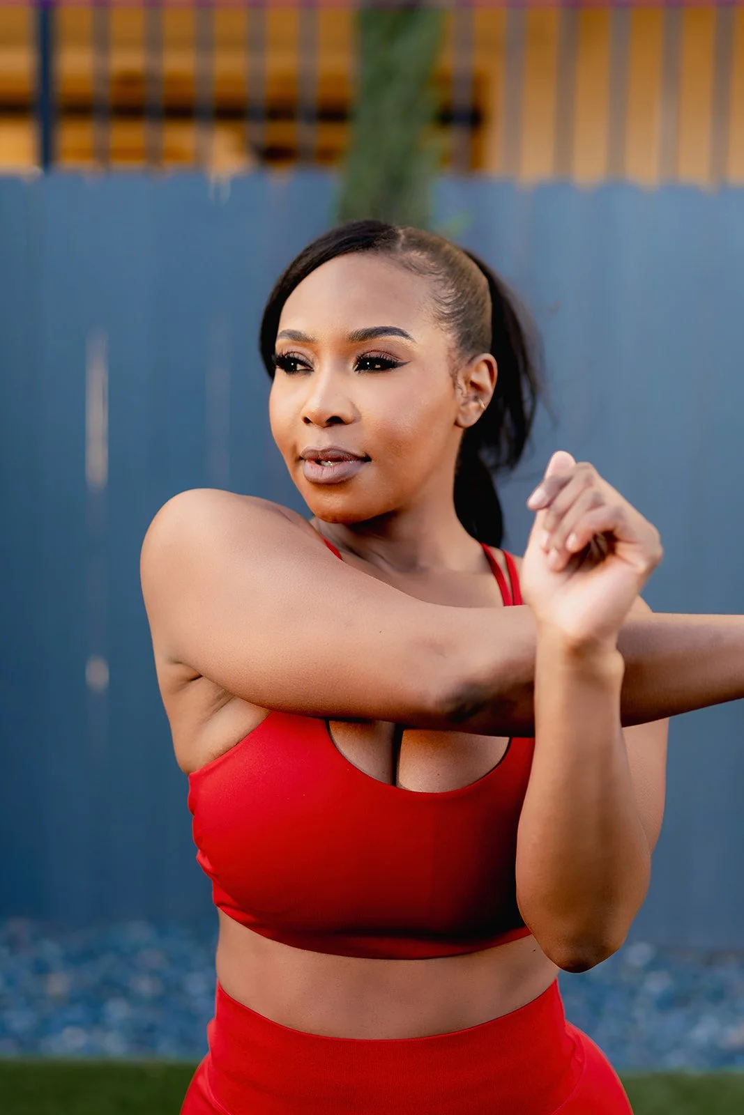 Woman in red sports bra stretching outdoors