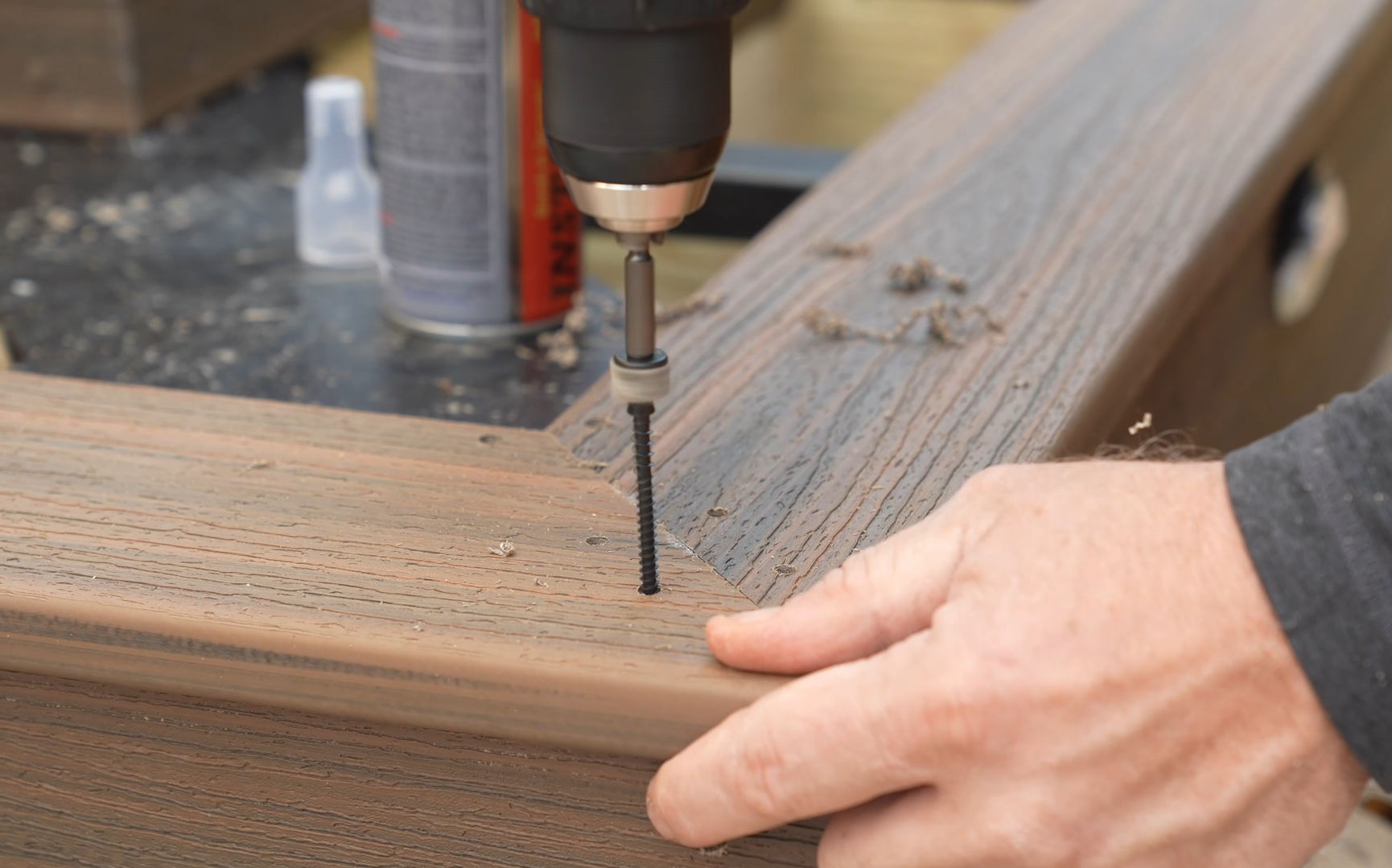 Person using a power drill to insert a screw into a piece of wood in woodworking or furniture assembly.