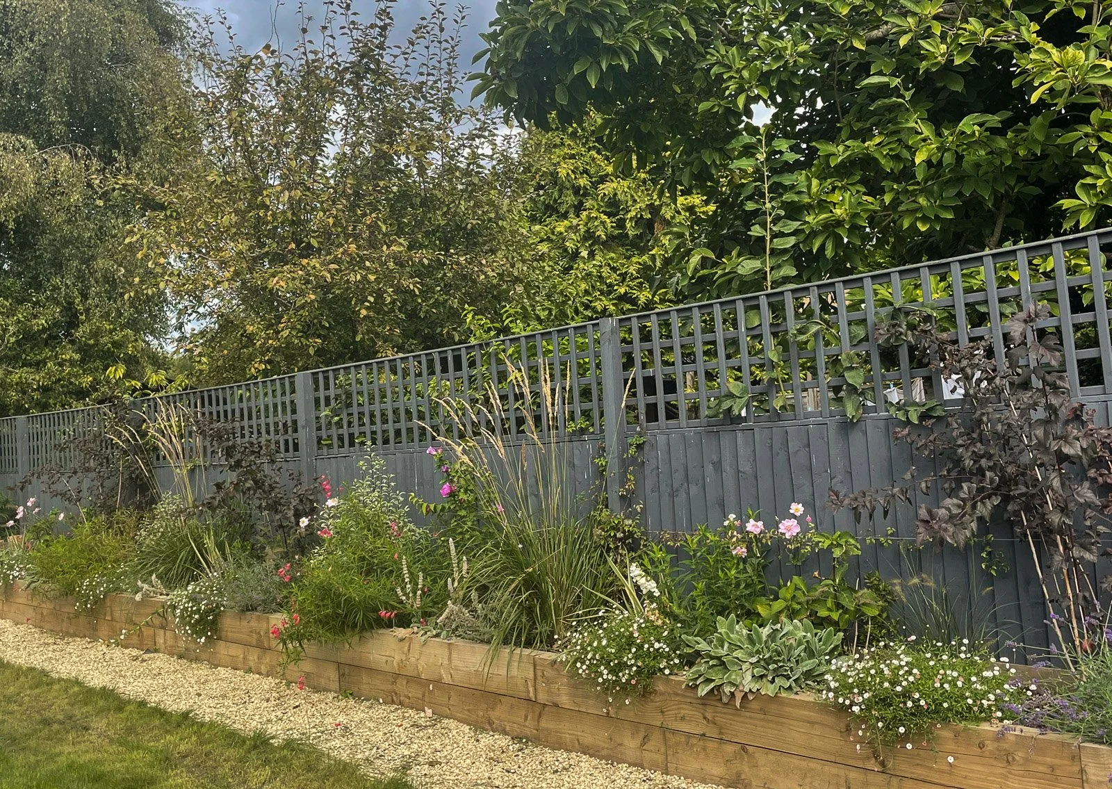 A range of grasses, perennials and climbers soften this fence