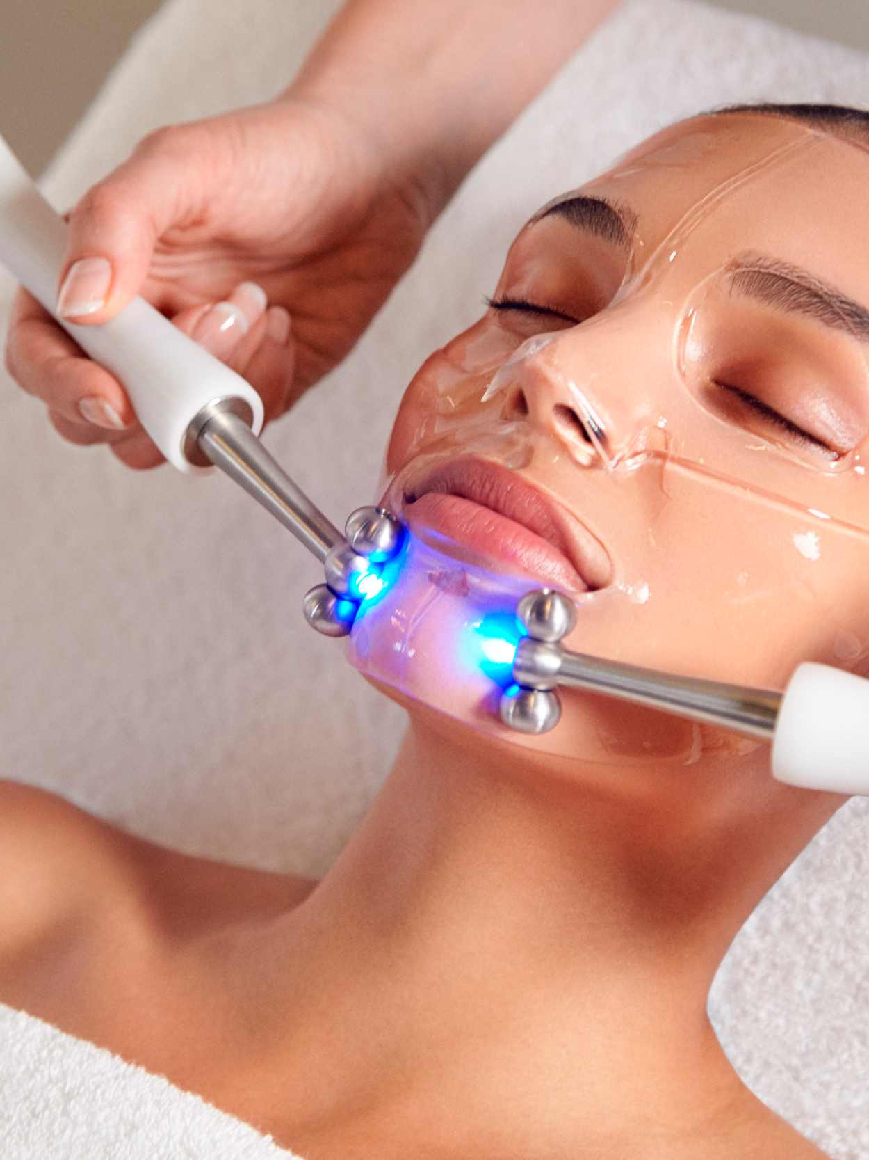 A woman receives a CACI facial anti-ageing treatment with Hydratone S.P.E.D® Dual Action Technology Rollers are used to gently massage the face over the electrically conductive CACI Hydro Mask