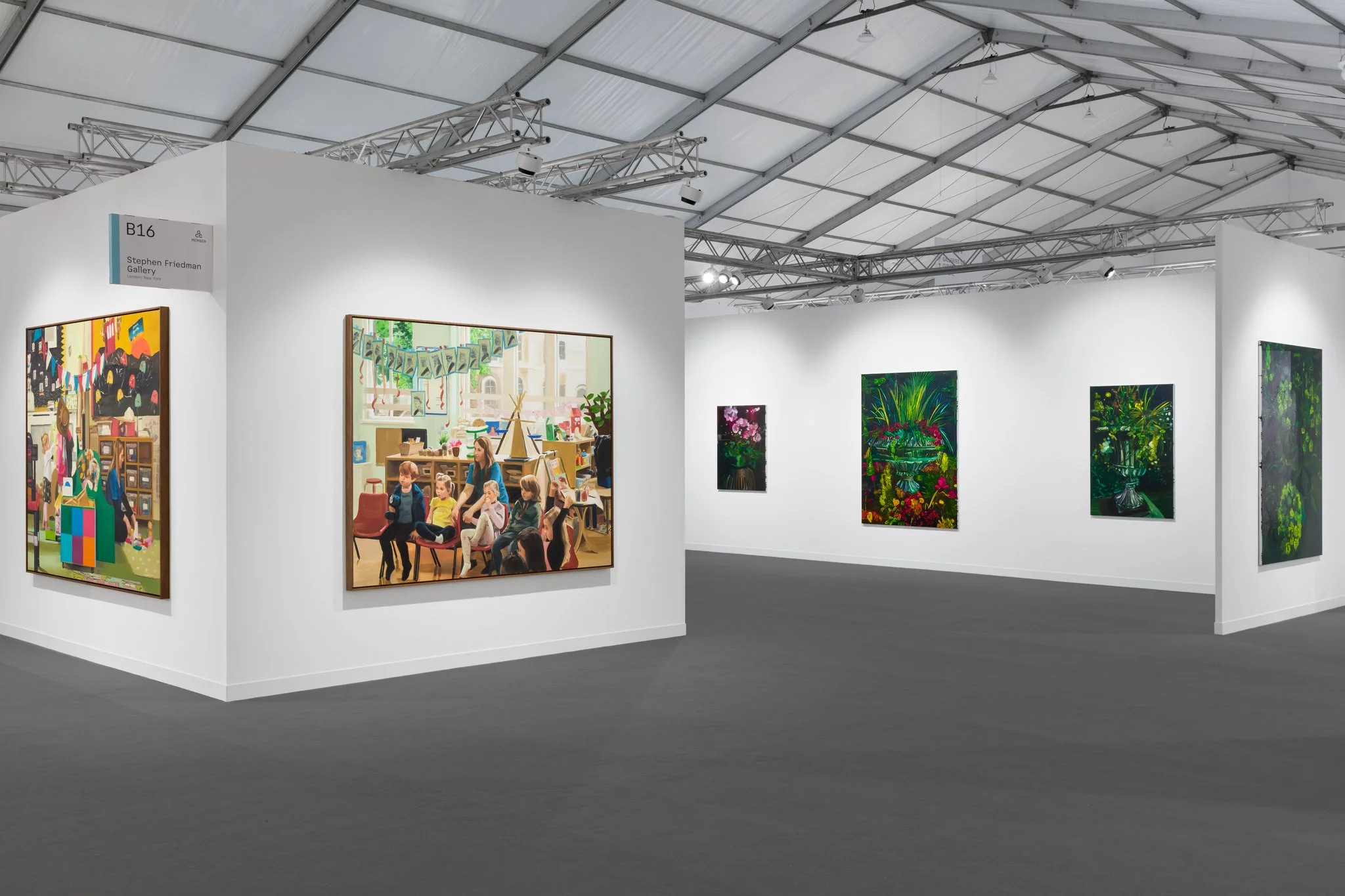 View of an art fair booth with white walls and various colourful paintings displayed.