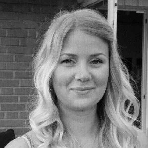 Headshot of a young woman with long, wavy hair, smiling slightly, in black and white.