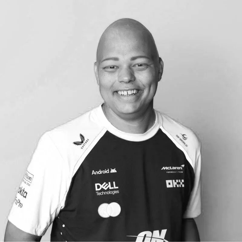 Black and white photo of a young man smiling, wearing a sports jersey with various sponsor logos.