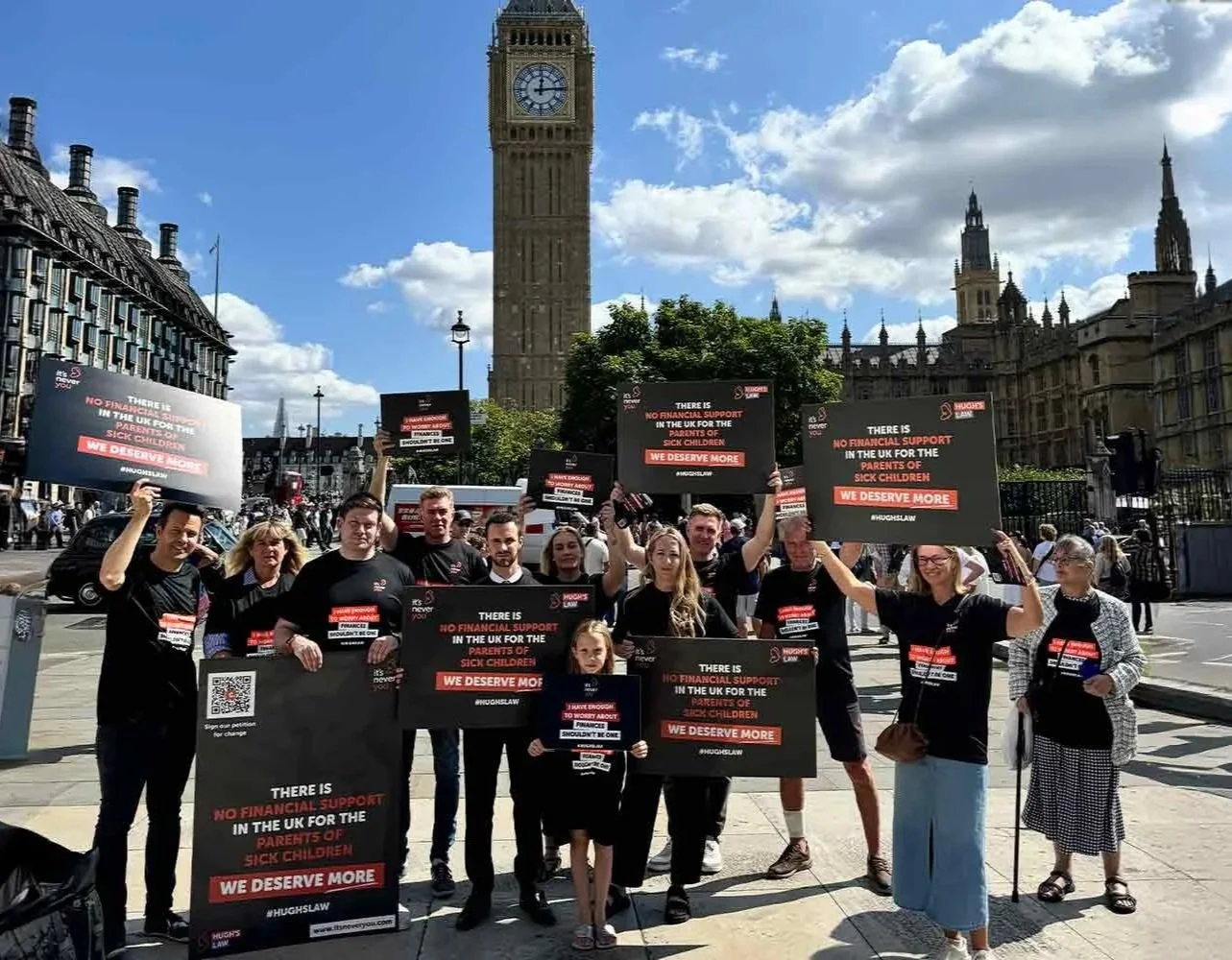 A group of protesters holding signs in front of Big Ben in London, advocating for increased financial support for parents of sick children.