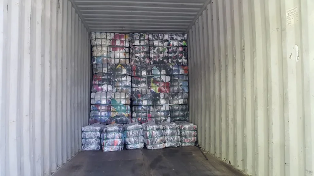 A shipping container filled with bags of plastic bottles, stacked neatly for storage or transport.