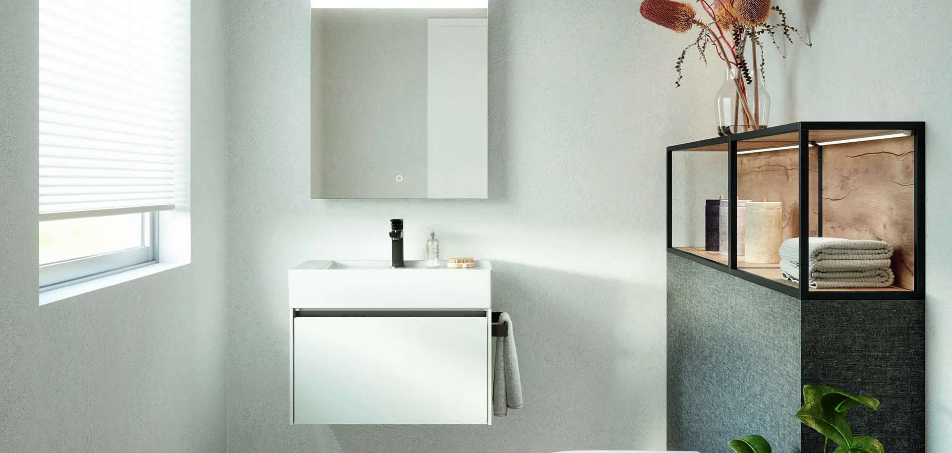 Minimalist bathroom with a small white vanity, a mirror, a black faucet, and a set of bathroom accessories on the counter. There is a window with blinds on the left and a black and wood shelf on the right with decorative items, towels, and a glass va
