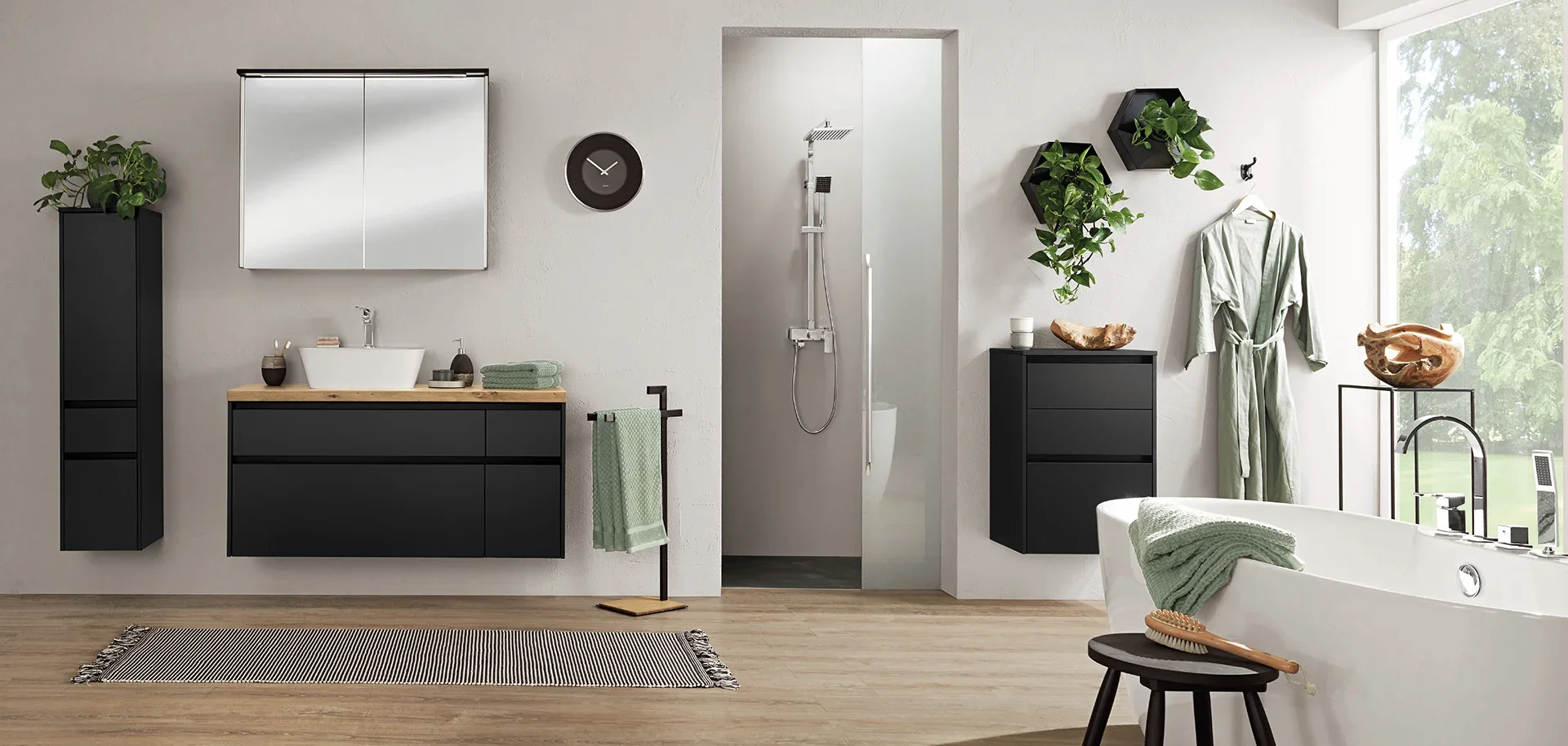 Modern bathroom with black cabinetry, a white bathtub, and green plants, illuminated by natural light through a large window.