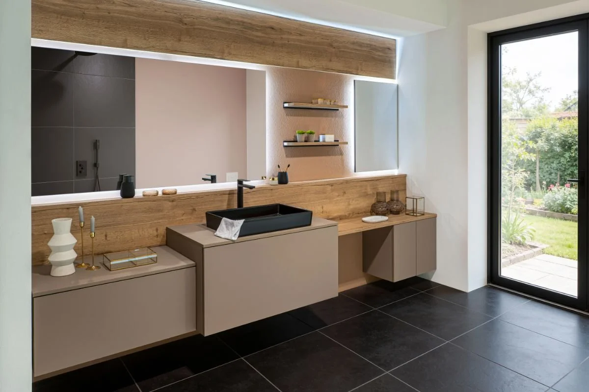 Modern bathroom with beige cabinetry, black sink, wooden accents, and a large window showing a garden outside.