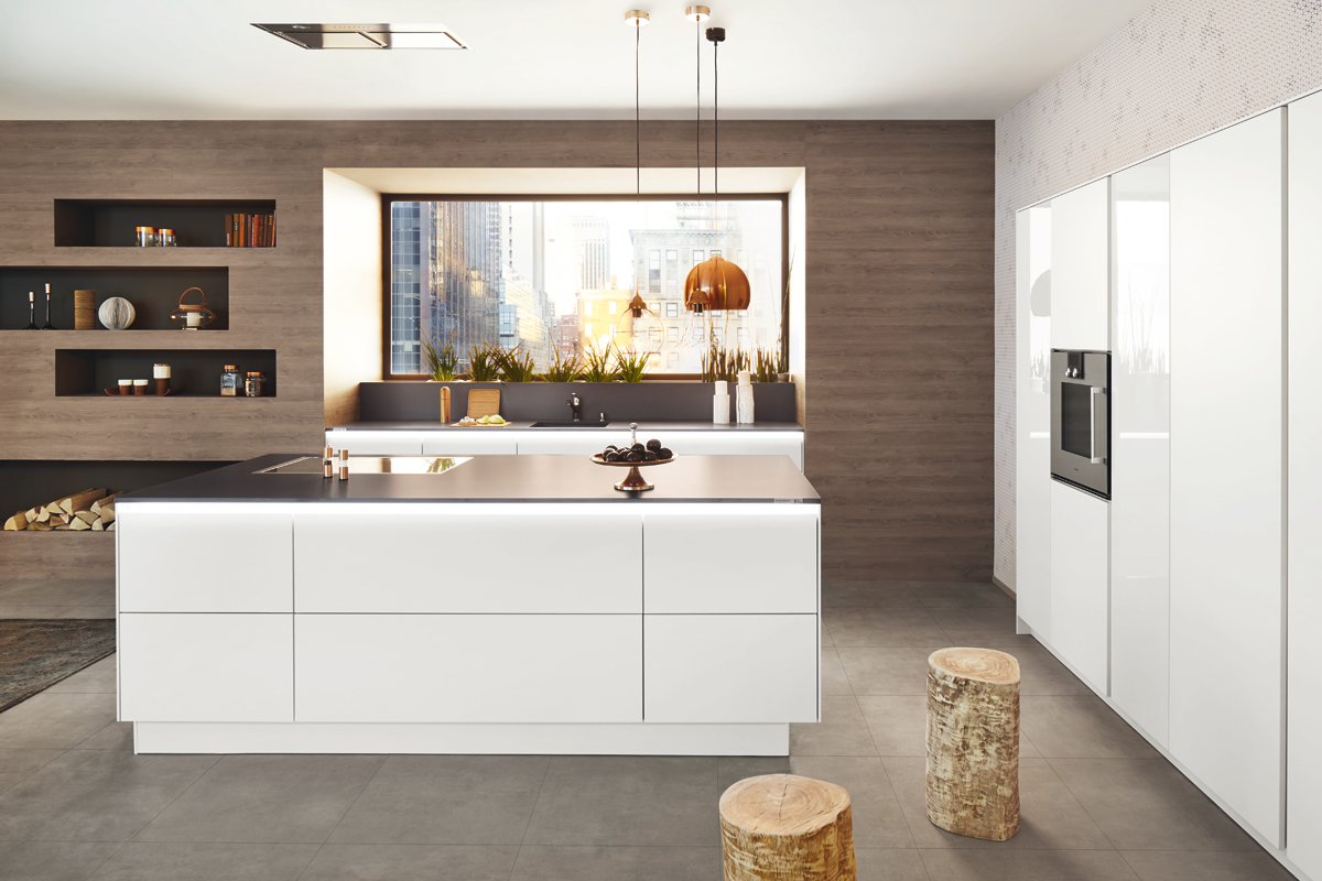 Modern kitchen with white cabinets, a large kitchen island, a window with city views, and decorative hanging pendant lights.