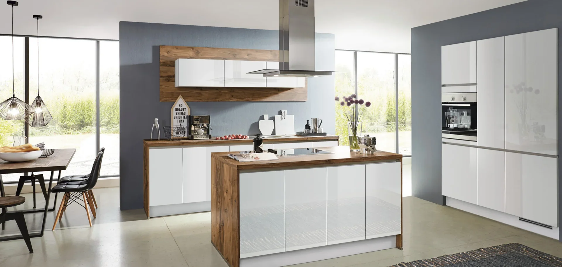 Modern kitchen with white cabinets, wooden accents, and large windows with a view of greenery outside.