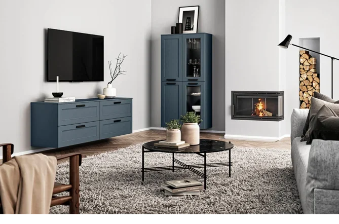 Living room with a TV mounted on the wall, a blue sideboard, a blue display cabinet, a fireplace, a table with vases, and a sofa.
