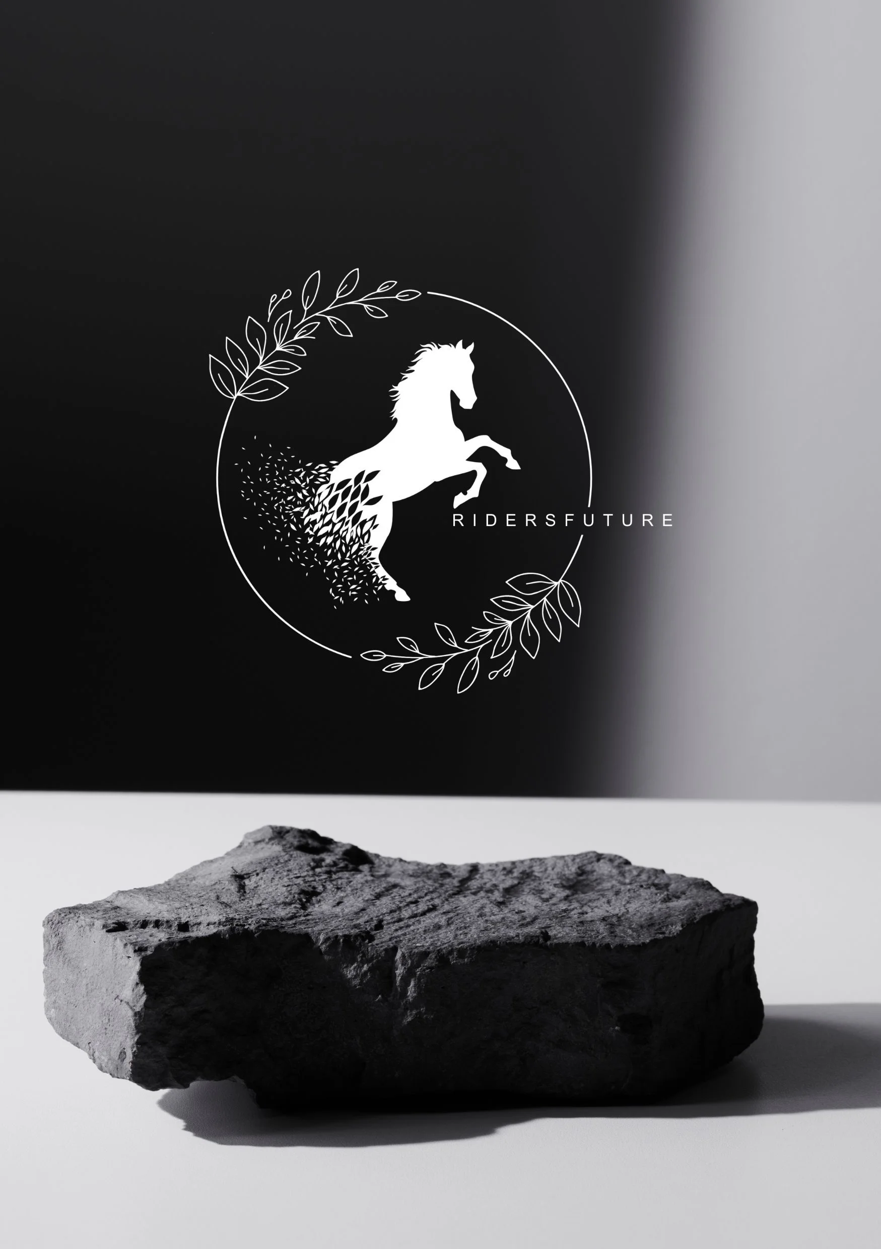 Schwarzes Foto mit weißer Illustration eines galoppierenden Pferdes und dem Text 'RIDERSFUTURE', umgeben von Blättern. Im Vordergrund liegt ein grauer Stein auf weißem Hintergrund.