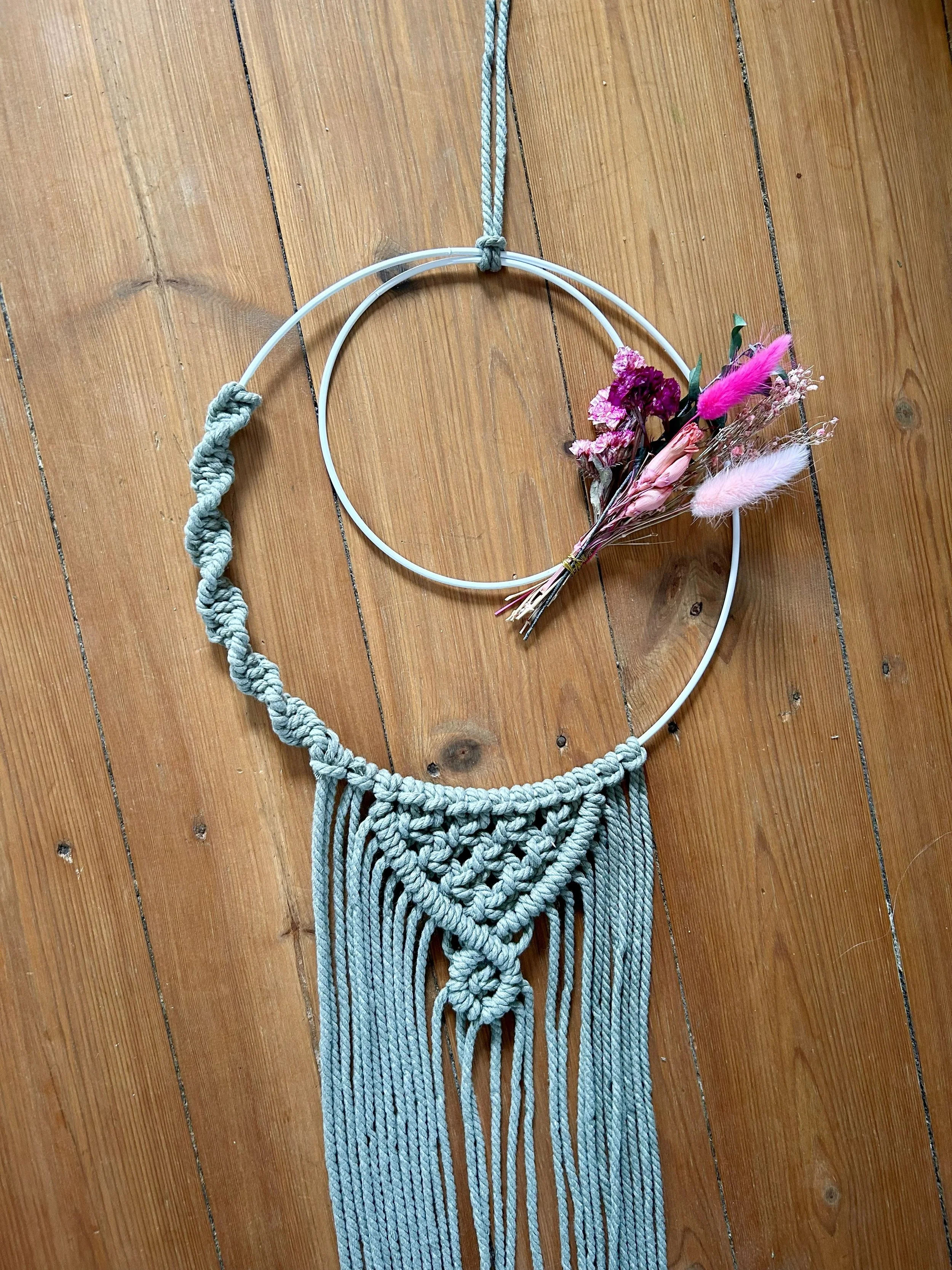 Makramee-Wanddeko mit Blumen auf Holzboden