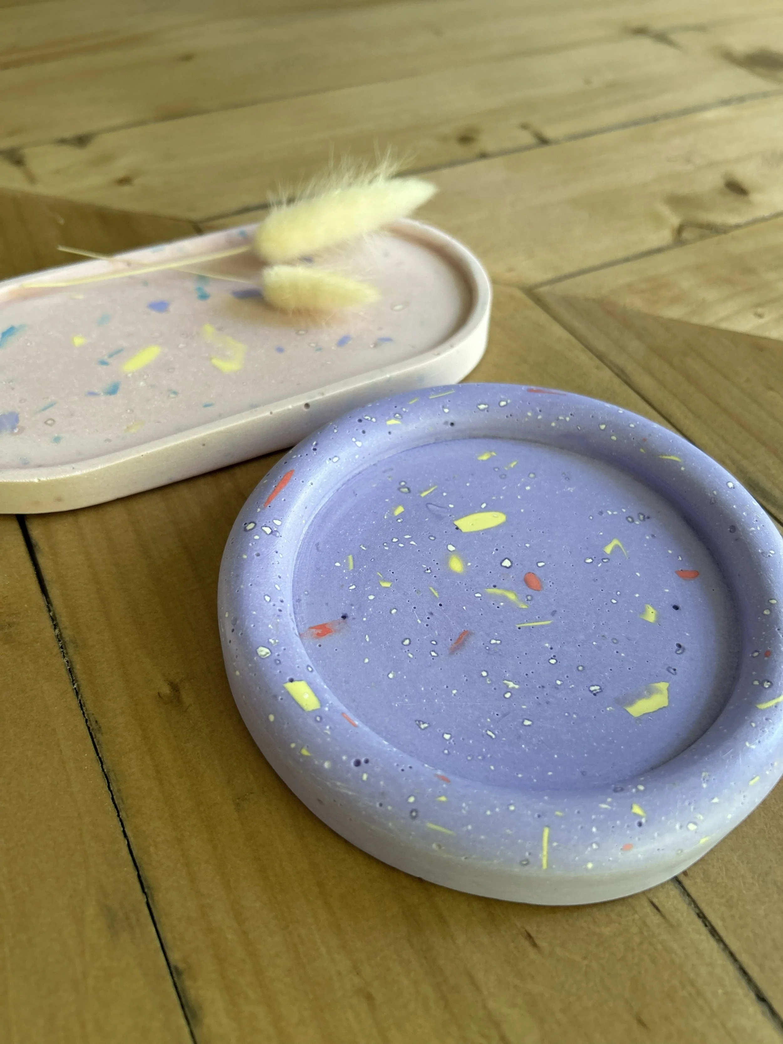 Mehrere Dekoartikel, die aus Jesmonite hergestellt wurden in verschiedenen Formen und Farben, auf einem Holztisch.