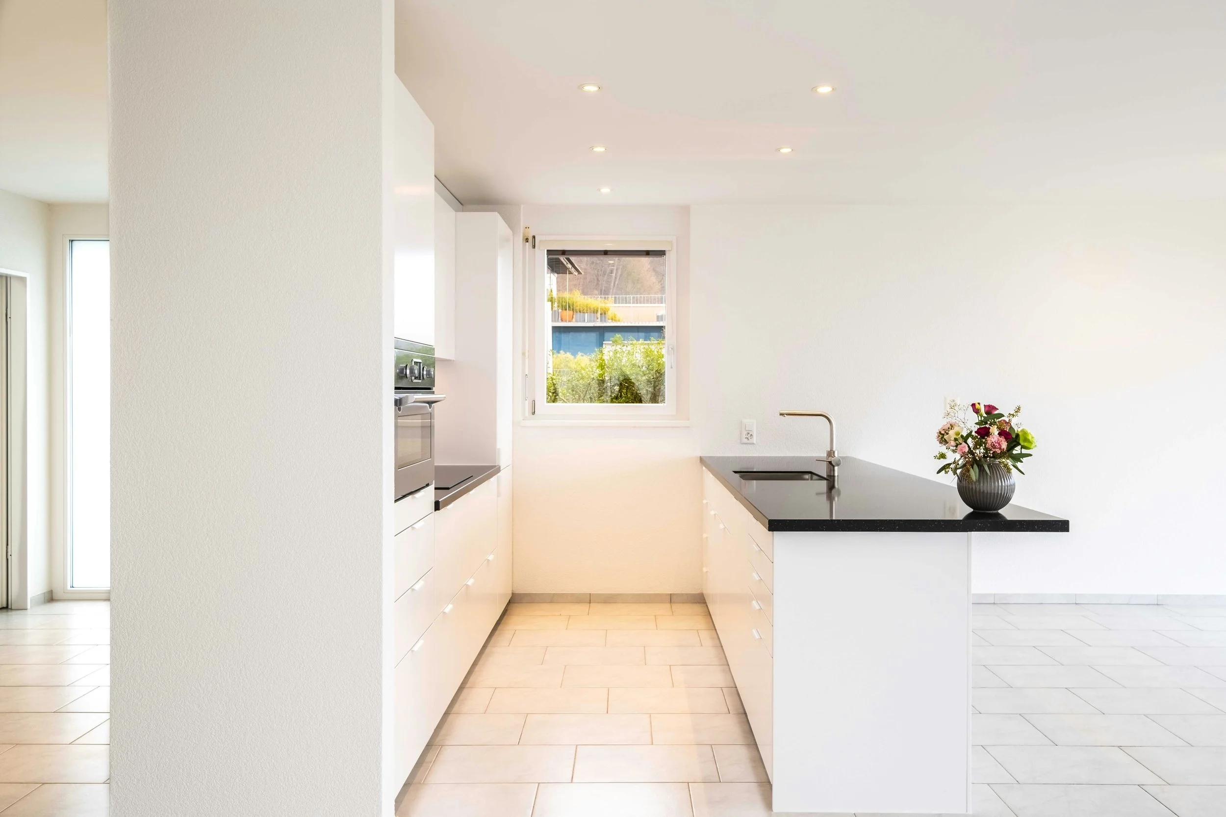 Modern kitchen with white cabinets, black countertop, and a vase of flowers on the island