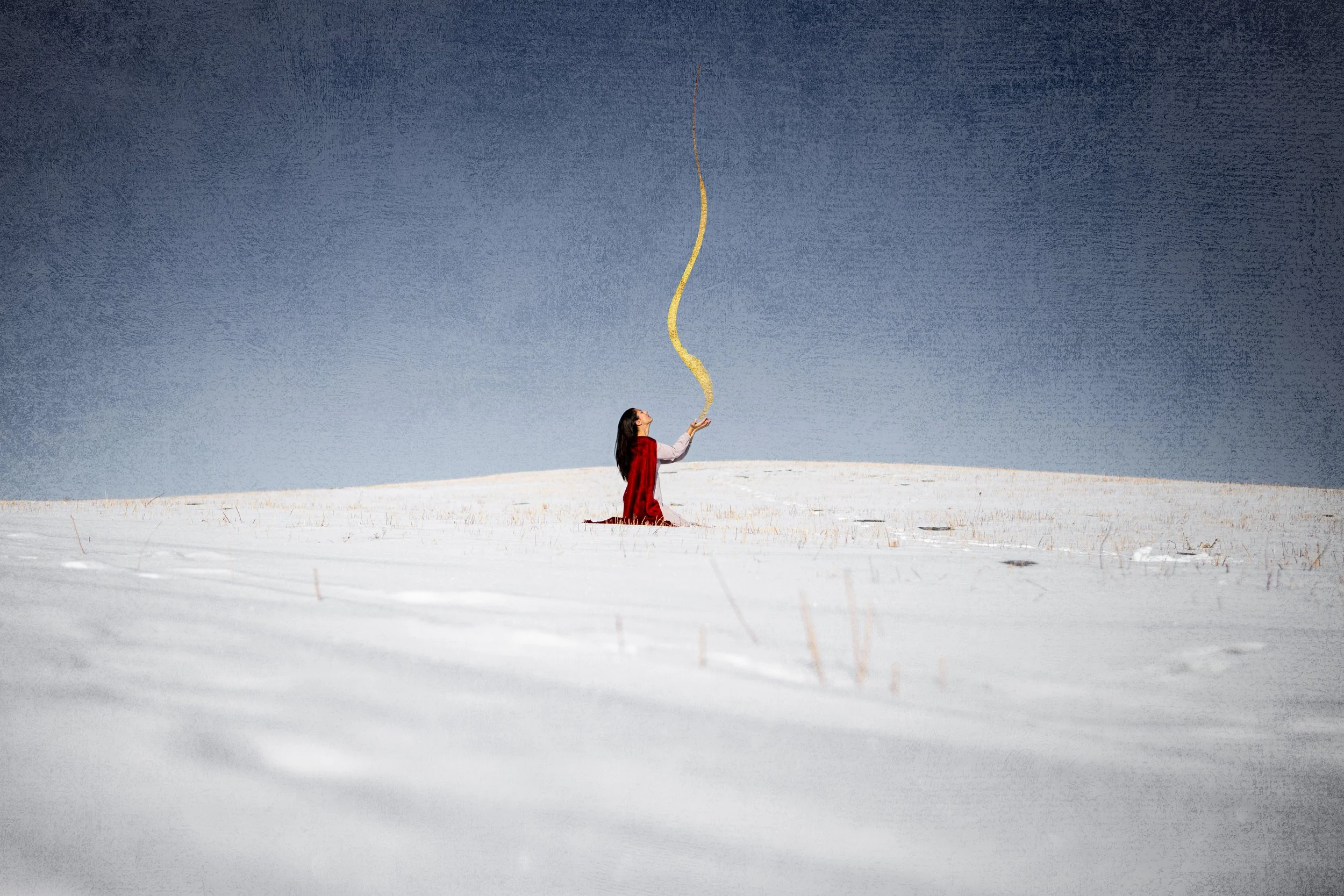 Woman kneeling in snow-covered field, holding a swirling trail of gold dust or light above her outstretched hand, with a dark blue sky in the background.