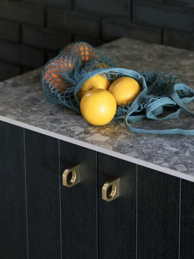 Yellow lemons inside a blue mesh reusable shopping bag on a gray granite kitchen countertop.