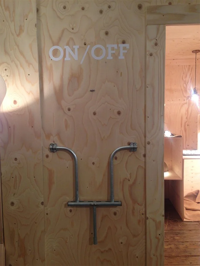 A wooden wall with a sign that says "ON/OFF" and a metal pipe attached beneath it.