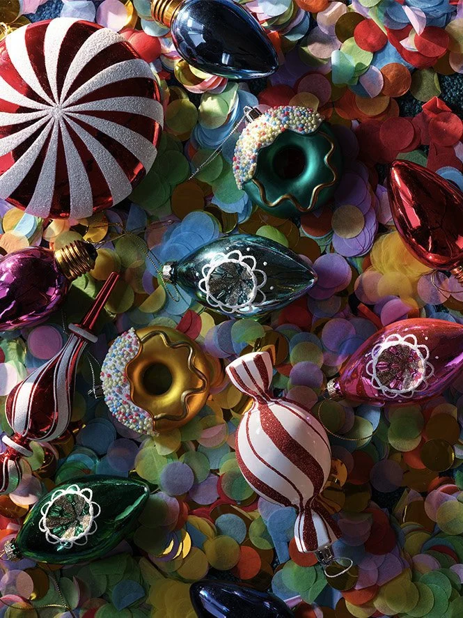Colorful Christmas ornaments and confetti on a surface.