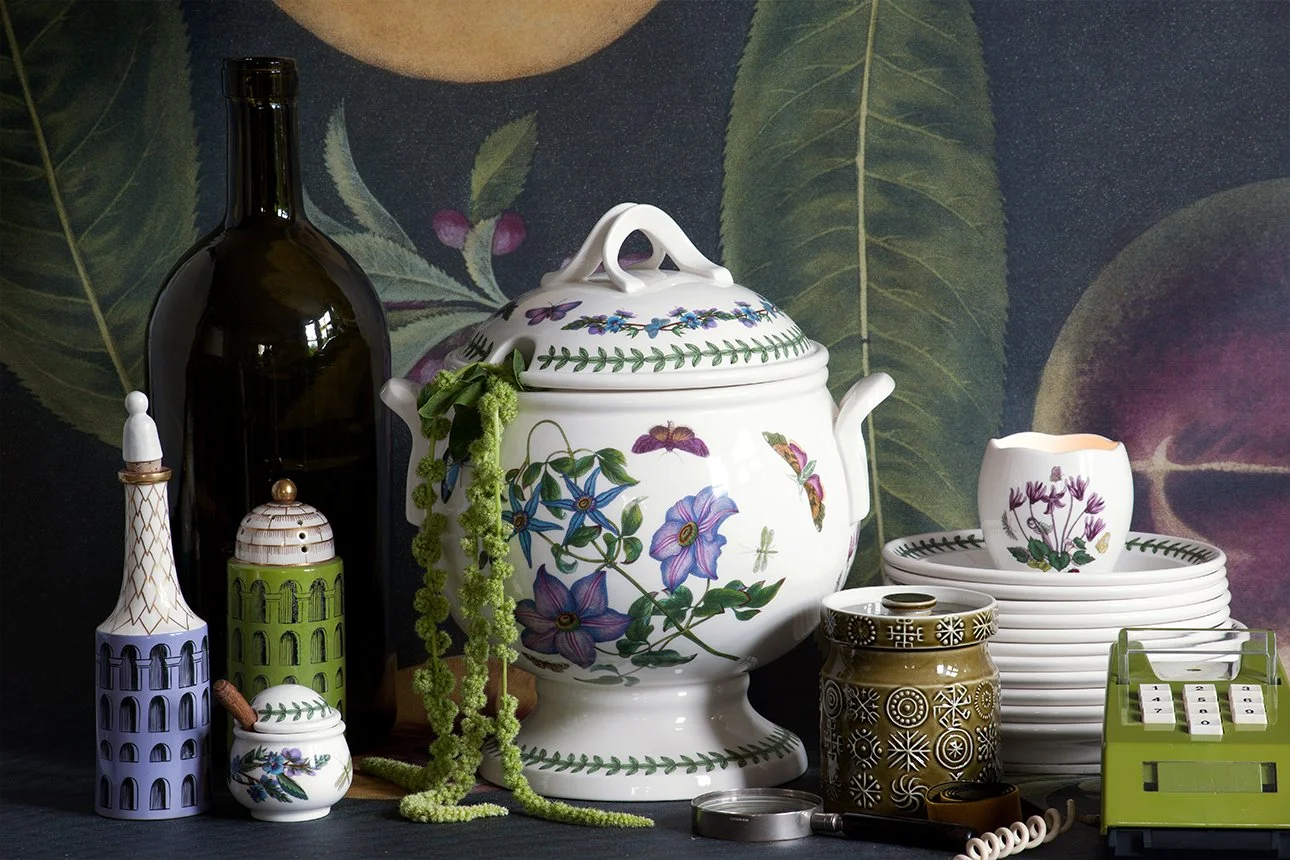 Decorative ceramics, jars, and figurines with floral and architectural motifs on a table with a dark background.