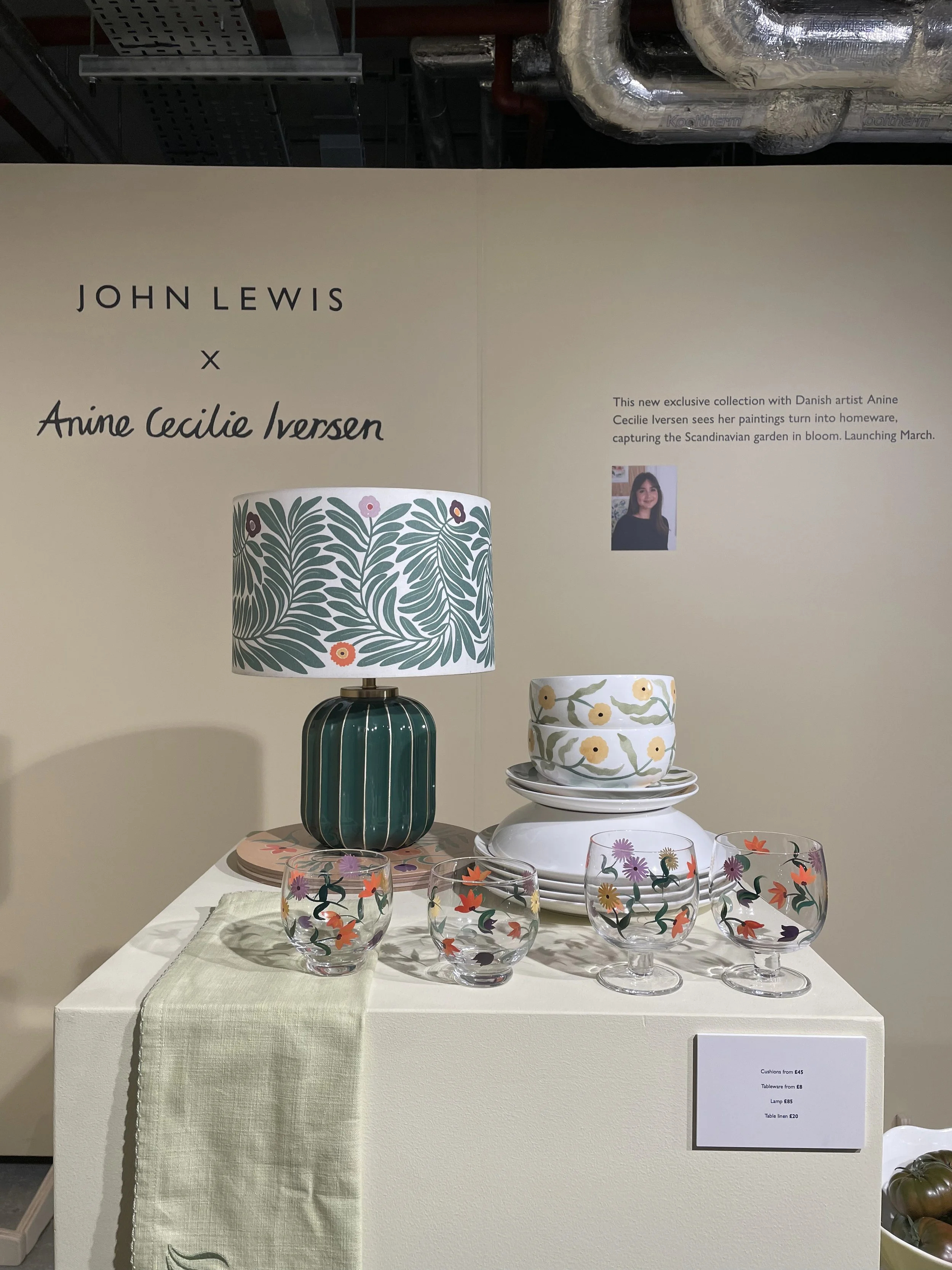 Display of decorative homeware including patterned lampshade, ceramic bowls, and painted glasses with floral designs, part of a collection by John Lewis and Anine Cecilie Iversen.