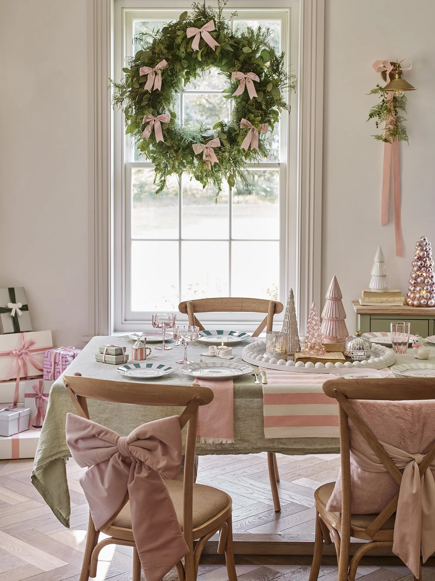 Christmas decorated dining room with a chandelier, decorated table, and a window with a wreath.
