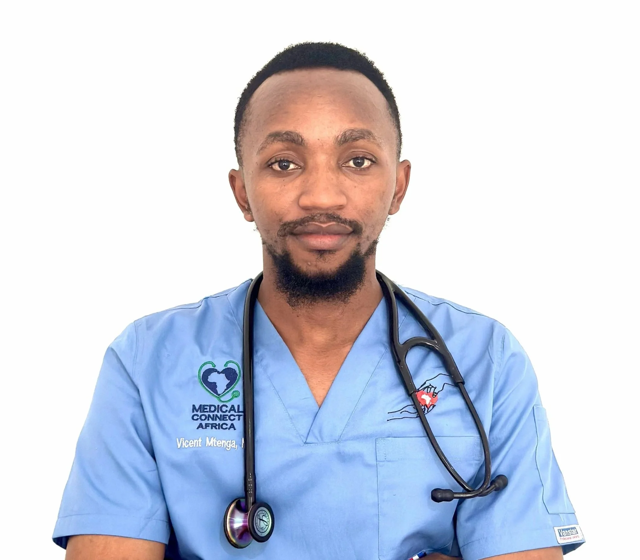 Portrait of a young man in a black shirt and tie, with short black hair and a goatee, against a plain background.