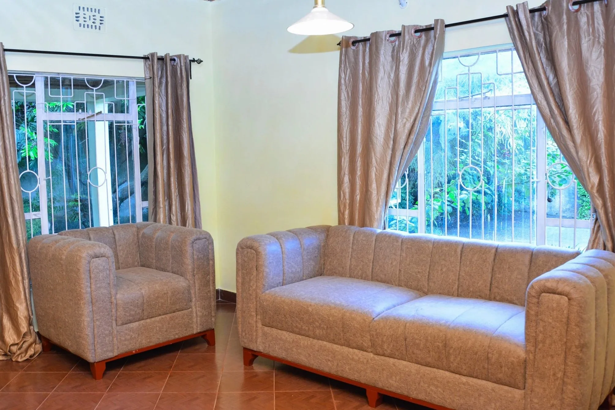 A mountain landscape features snow-capped peaks in the background and a modern house on a green hillside in the foreground.
