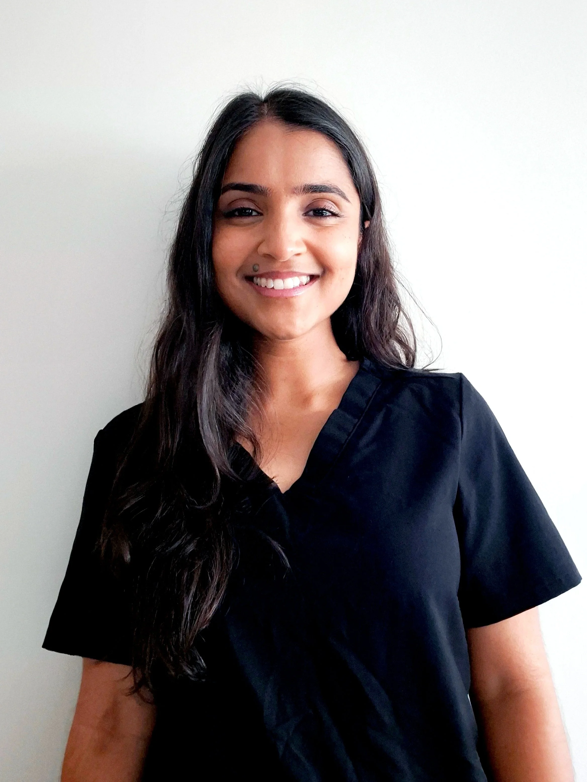 Two women dressed in costume, one as Spider-Man and the other in a poop emoji costume with green superhero costume behind, posing playfully indoors.