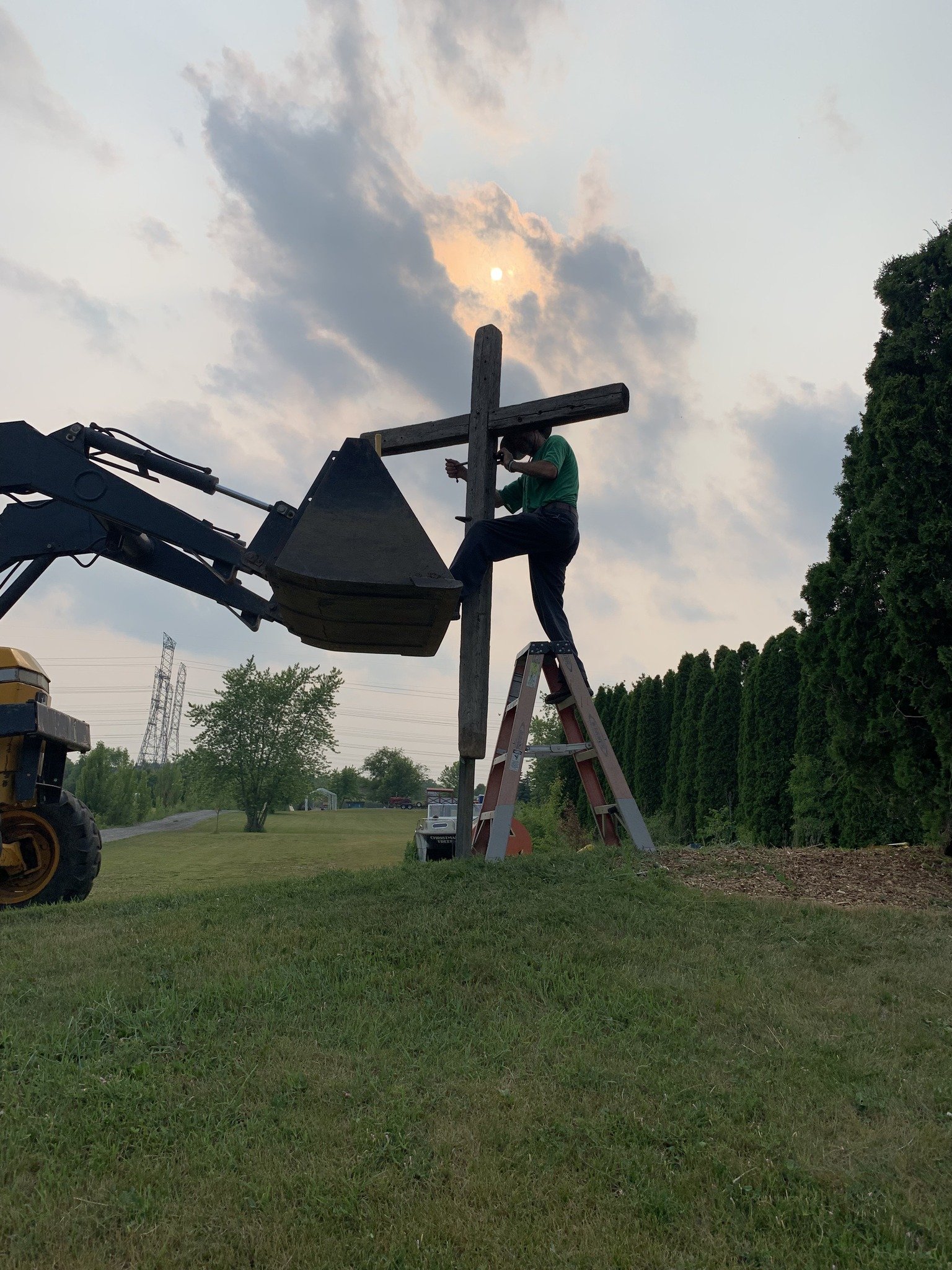 Rick and team installing a wooden cross on a utility pole using a cherry picker before the revival event.