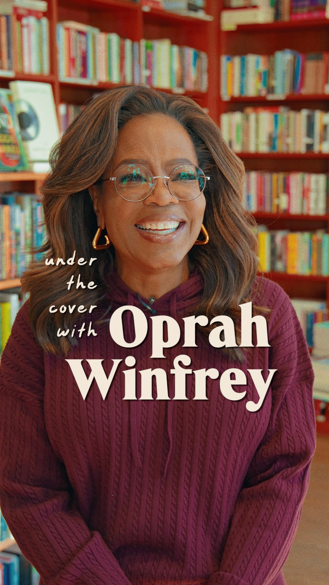 Cover image of a book titled "under the cover with Oprah Winfrey" featuring Oprah Winfrey smiling in a library, wearing glasses and a maroon sweater, with bookshelves in the background.
