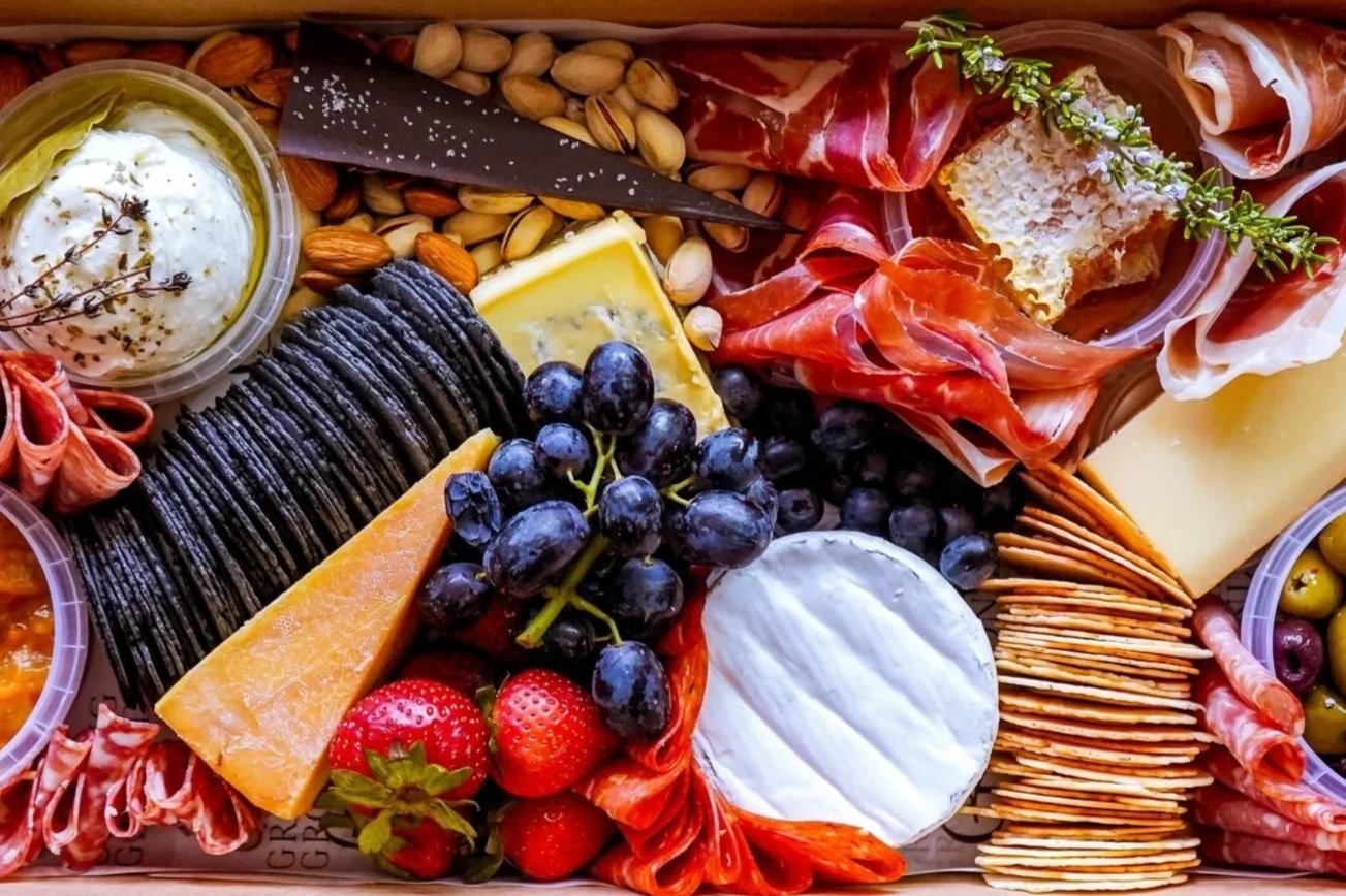 Luxury grazing box featuring artisan cheeses, cured meats, fresh fruit, crackers and gourmet accompaniments.