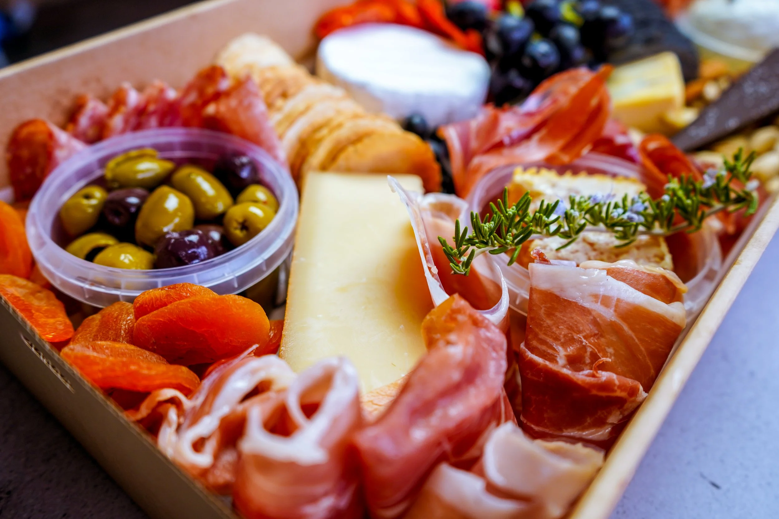 Marinated olives, artisan cheeses and cured meats arranged in a handcrafted grazing box.