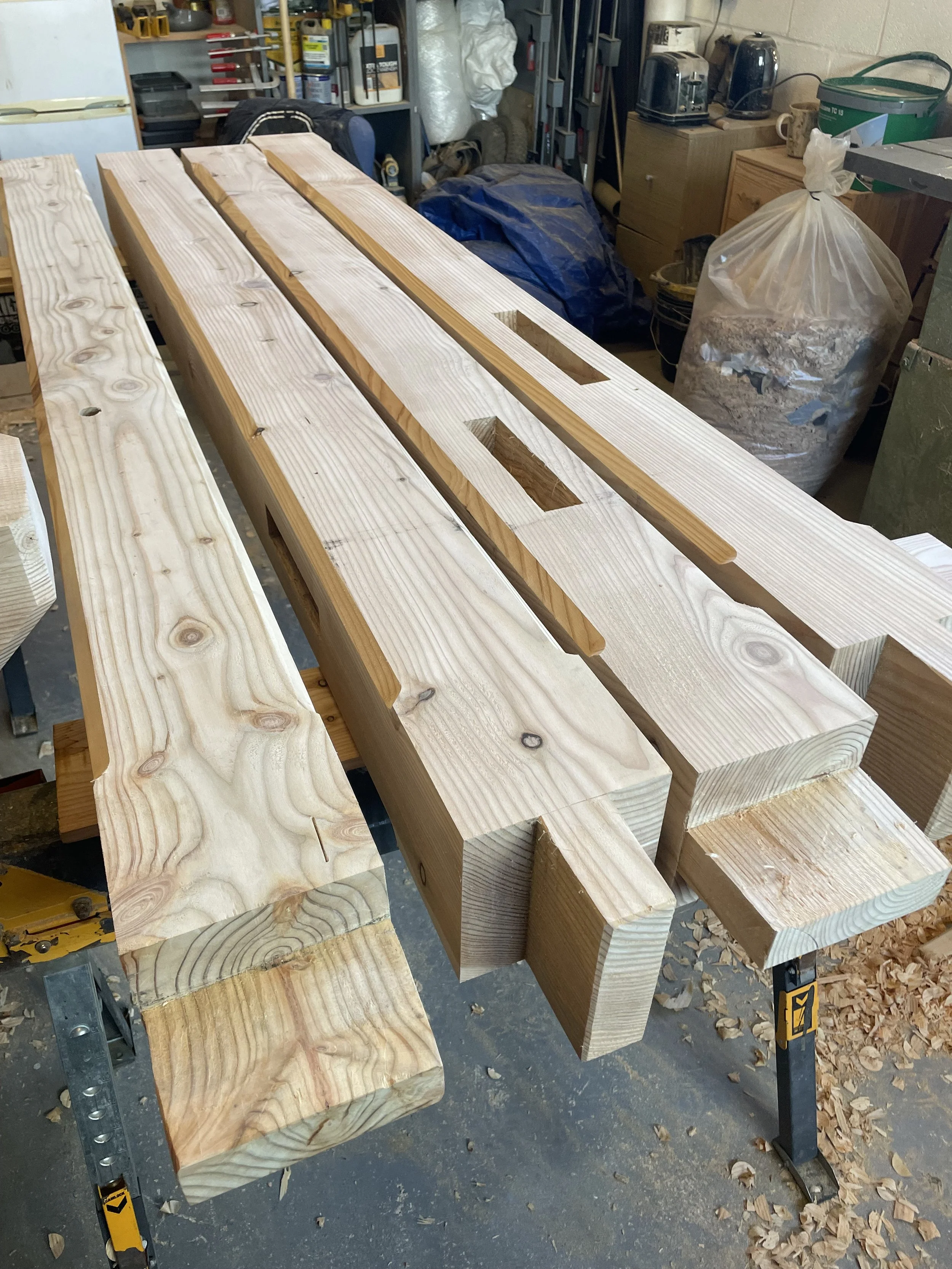 Several pieces of cut and sanded wood laid out on workbenches in a woodworking workshop.