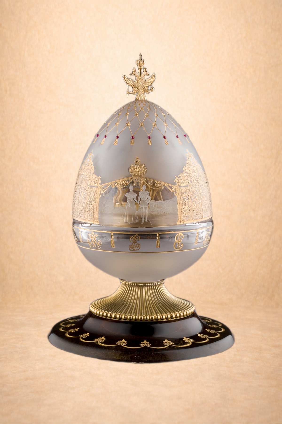 Ornate egg-shaped jewelry box with gold and silver detailing, featuring a crown on top, a miniature scene inside, and a decorative black and gold base.