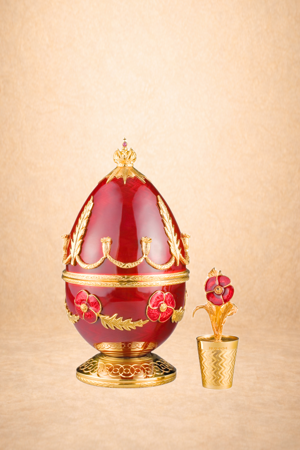 Decorative red and gold crown and a red floral urn with gold accents on a golden surface with a plain background.