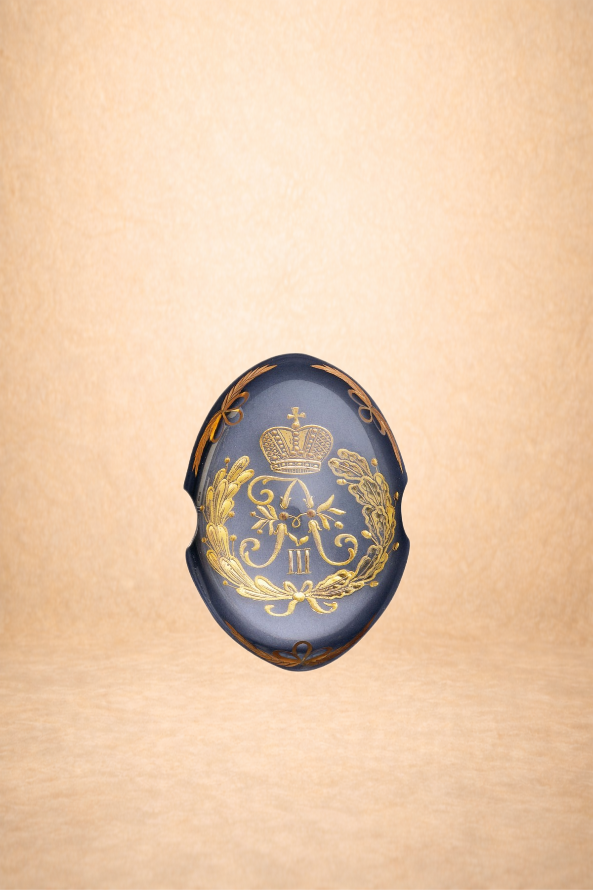 Decorative navy blue ceramic plate with gold embroidery featuring a crown, a laurel wreath, a face, and the Roman numeral III, set against a beige background.