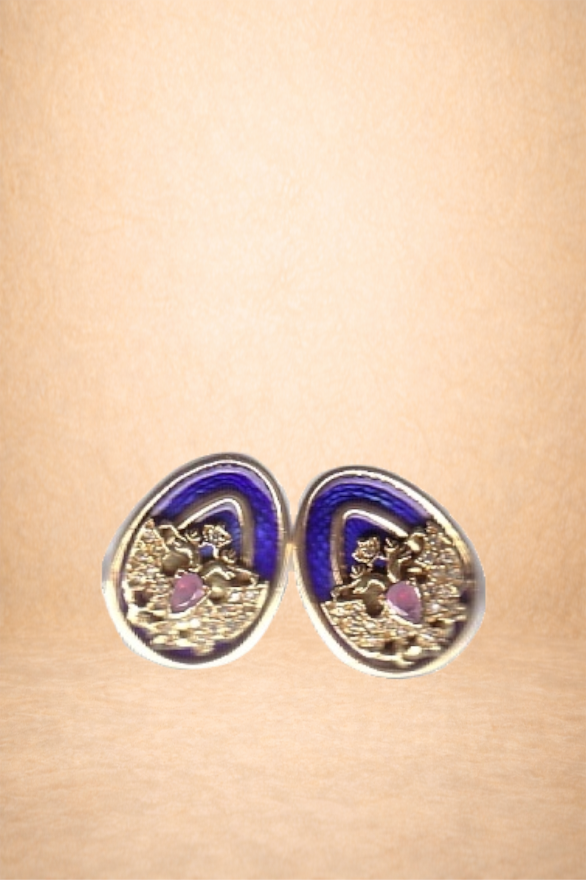 A pair of decorative earrings with pink stones and purple and gold accents on a beige background.
