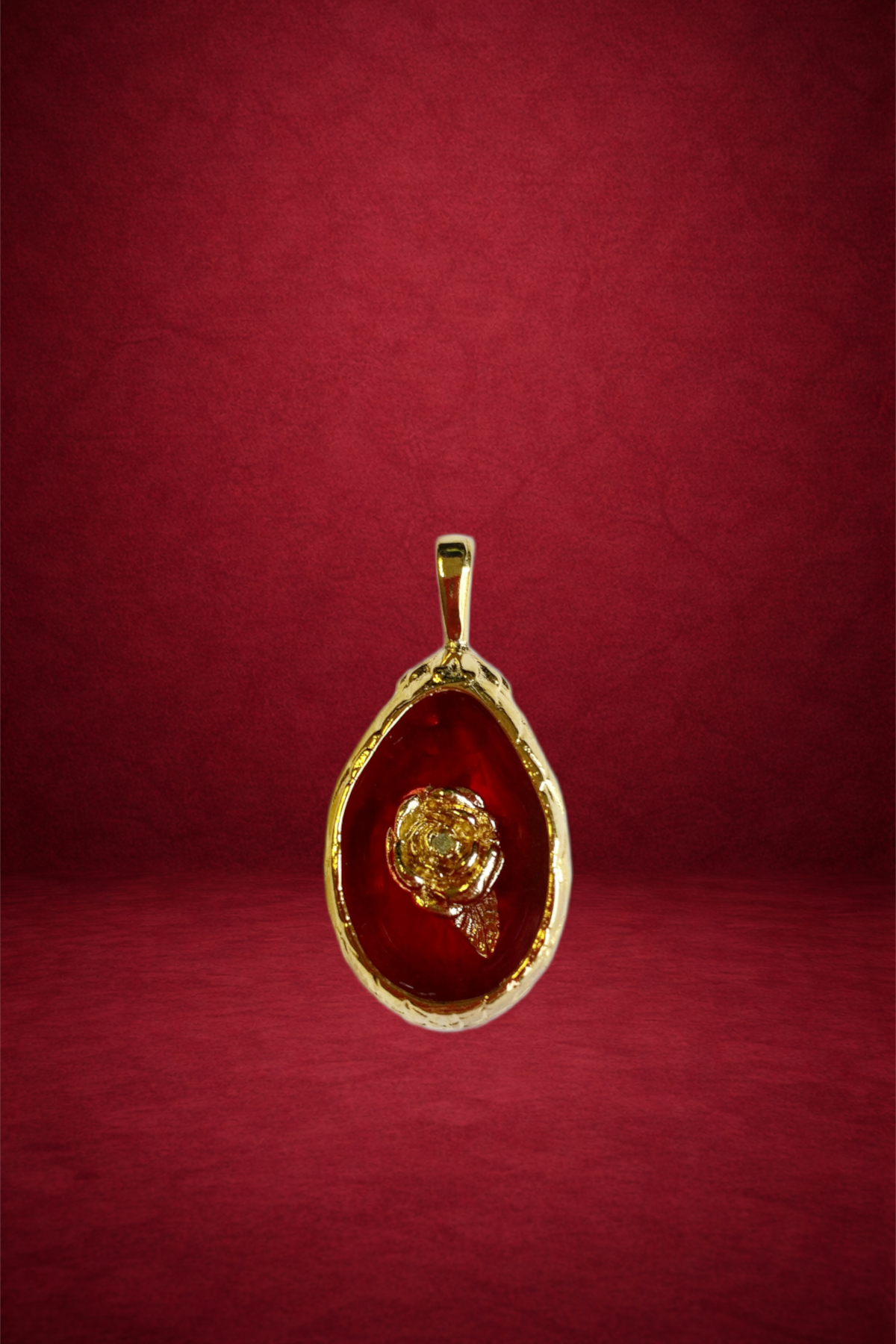 A gold pendant with a red gemstone background and a carved gold rose design in the center, hanging against a red textured background.