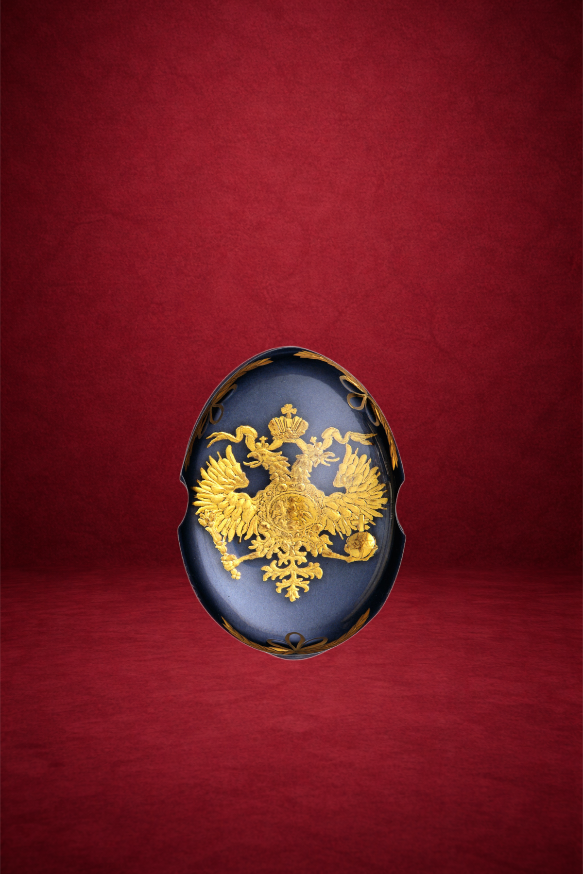 A decorative oval black and gold jewelry box with a double-headed eagle emblem on the lid, set against a red background.