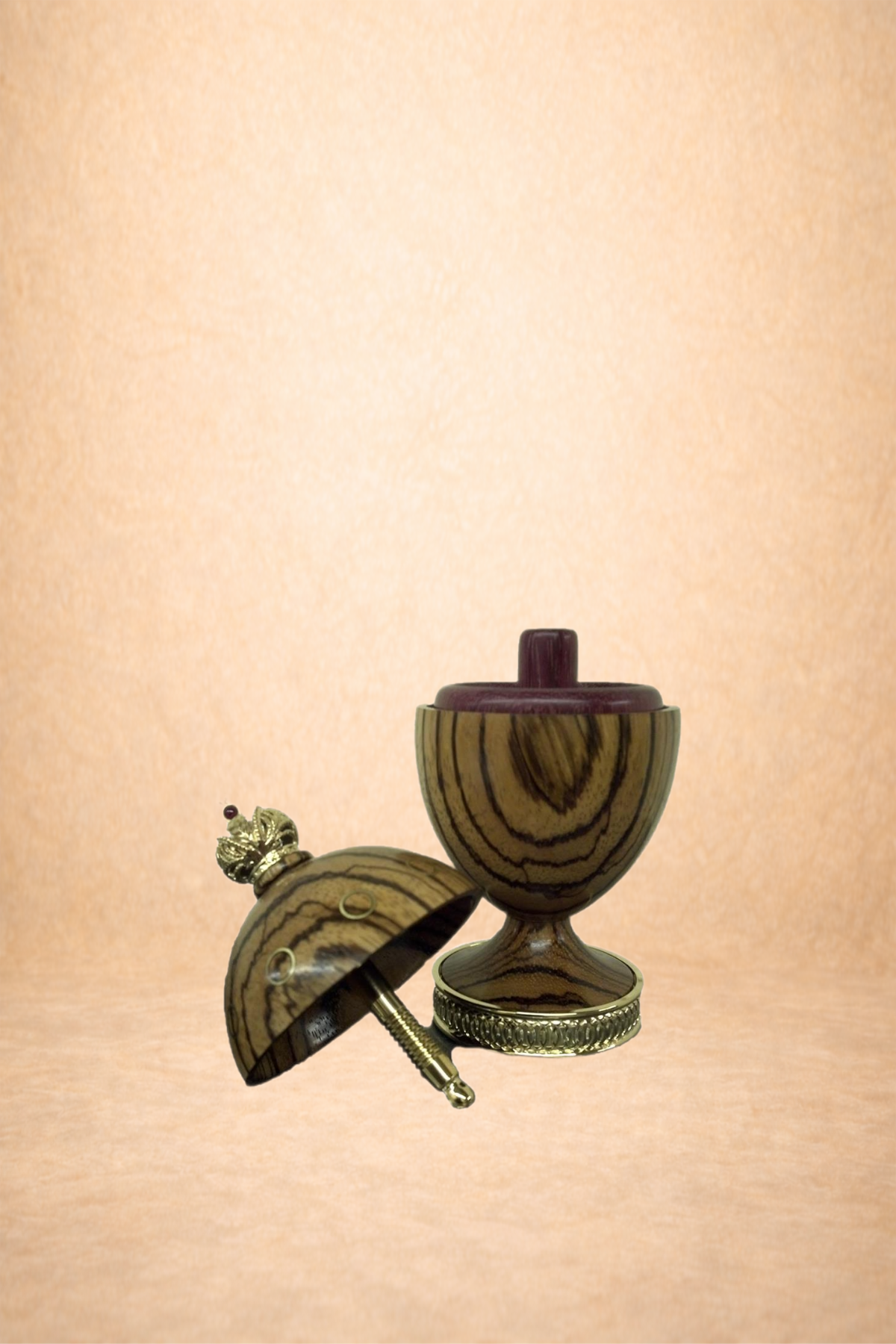 Decorative wooden egg cup with a detachable lid, pink interior, and gold accents, placed on a soft pink background.