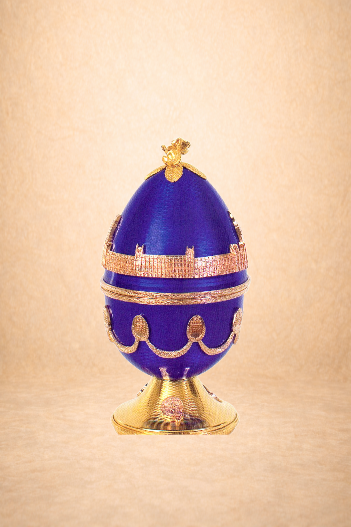 A decorative blue and gold egg-shaped container with intricate gold detailing, set against a light beige background.