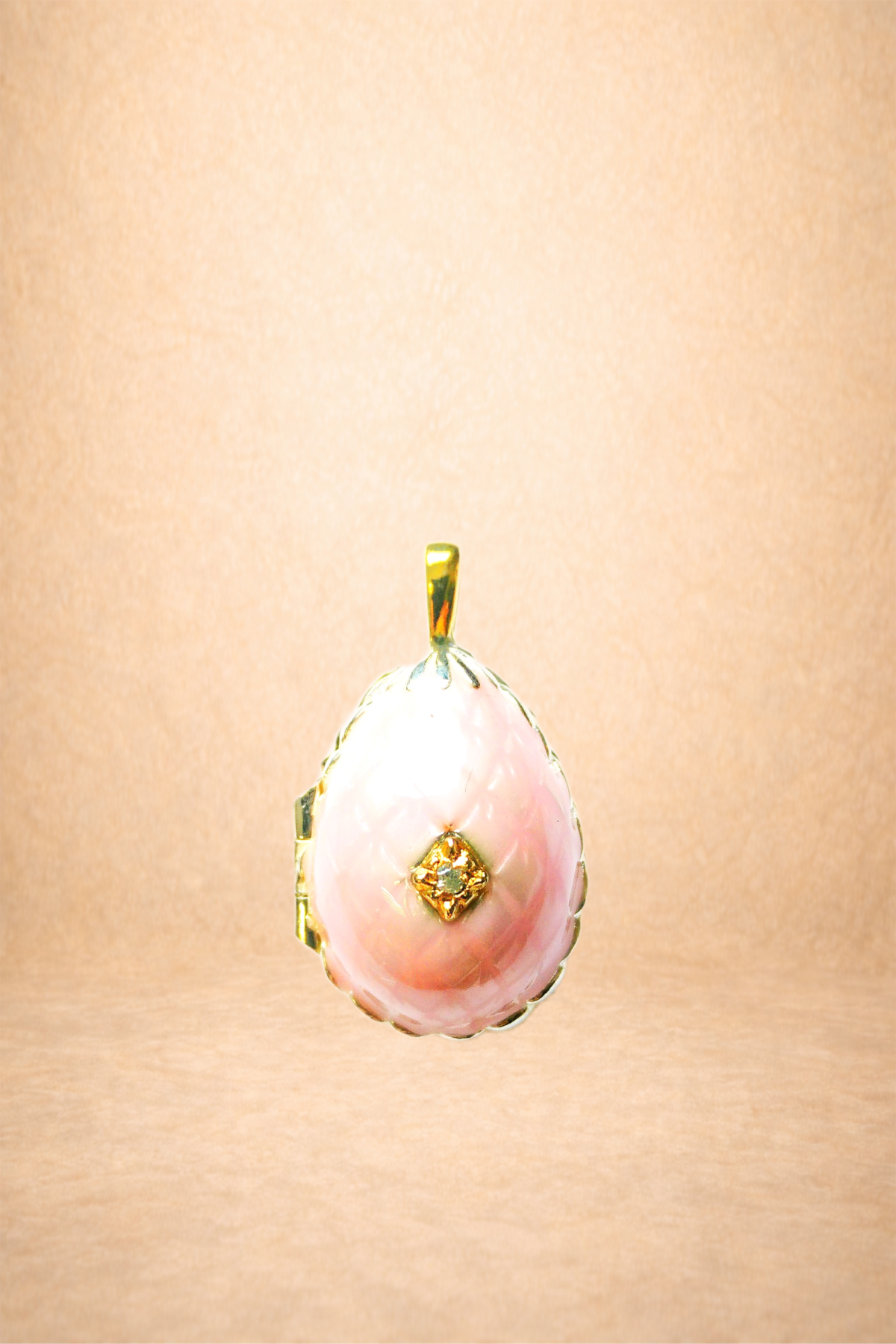 A pink pendant with a gold and diamond design.